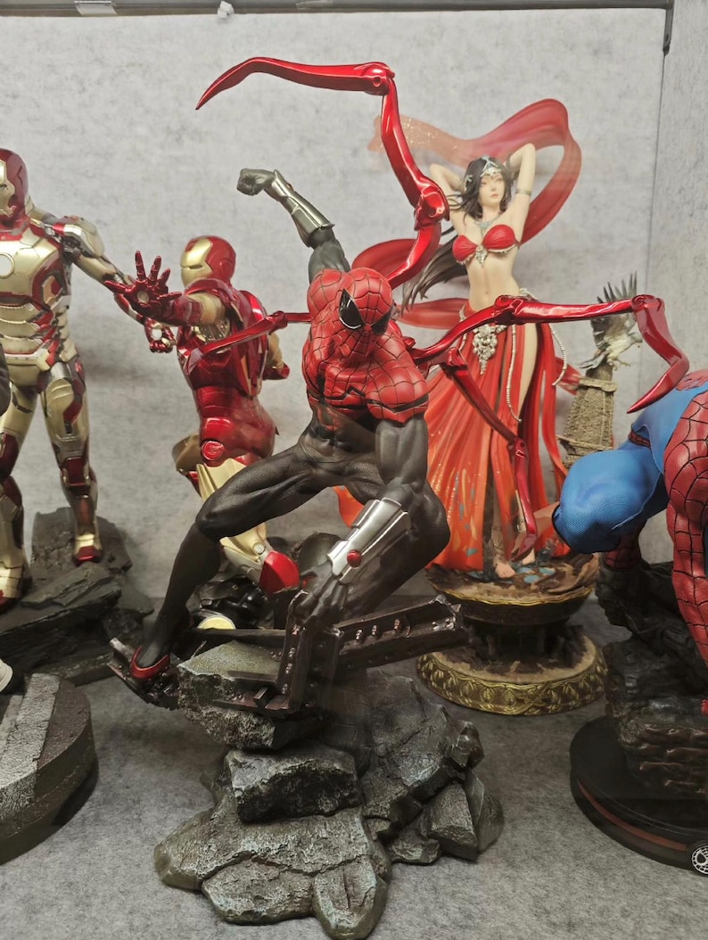 May include: A collection of superhero figurines, including Iron Man and Spider-Man, in dynamic poses. The Spider-Man figure is in a crouching position with red and black detailing. Other figures are in red and gold armor.