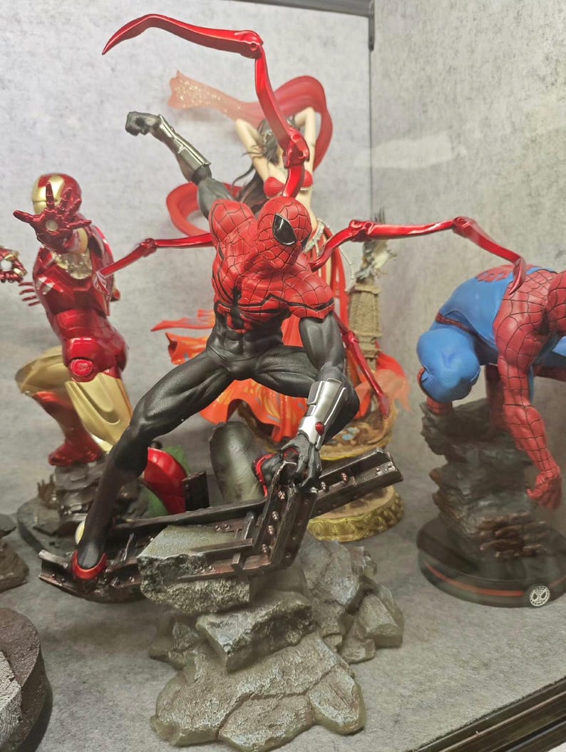 May include: A collection of superhero figurines, including Spider-Man in a dynamic pose with red and black suit, and Iron Man in a red and gold suit. Other figures include a woman in a red outfit and another Spider-Man figure.