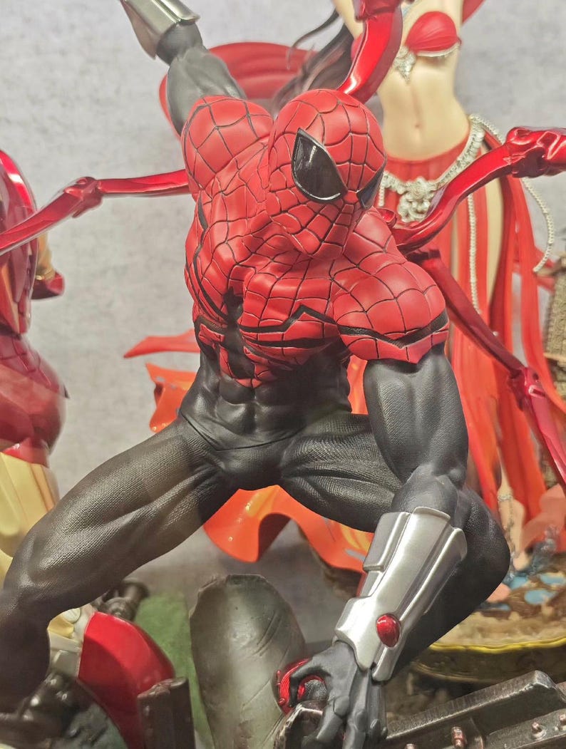 May include: A dynamic action figure of Spider-Man in a striking pose, clad in a red and black suit with intricate web detailing. The figure has a muscular build and is set against a backdrop with other figures.