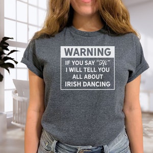 Puede incluir: Una camiseta gris con un cartel de advertencia blanco que dice "WARNING IF YOU SAY "Hi" I WILL TELL YOU ALL ABOUT IRISH DANCING"