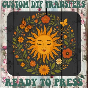 May include: A DTF transfer design featuring a smiling sun with closed eyes, surrounded by orange flowers, butterflies, and green leaves. The words "CUSTOM DTF TRANSFERS" and "READY TO PRESS" are printed above and below the design.