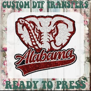 May include: A glittery red and white elephant head design with the word "Alabama" in a script font. The design is set against a white background with the text "CUSTOM DTF TRANSFERS" and "READY TO PRESS" in green.