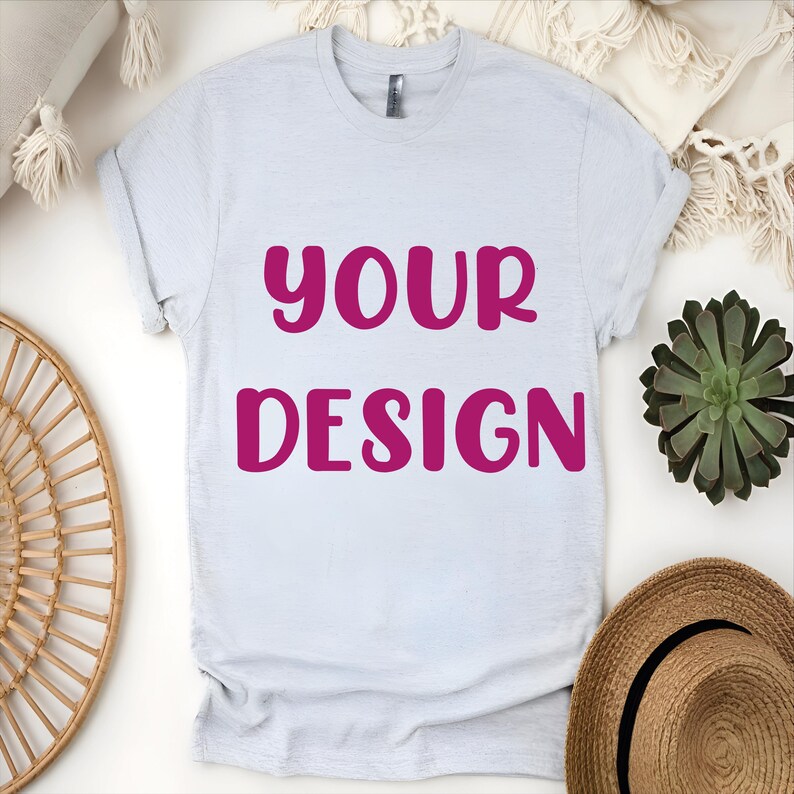 May include: A light gray t-shirt with the words "YOUR DESIGN" printed in pink.