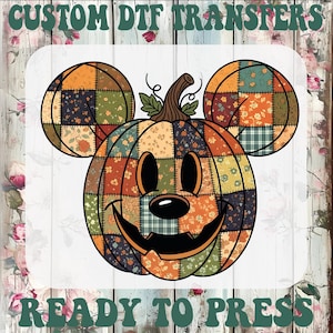 May include: A custom DTF transfer featuring a pumpkin shaped like a mouse head with a patchwork floral pattern in orange, green, and brown. The design includes a carved jack-o'-lantern face and the text CUSTOM DTF TRANSFERS READY TO PRESS.
