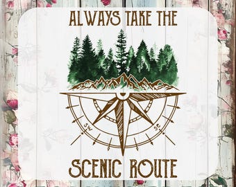 Könnte beinhalten: Ein weißer Hintergrund mit einem Kompass-Design und dem Text "ALWAYS TAKE THE SCENIC ROUTE". Das Design enthält ein Aquarellbild eines Waldes und von Bergen. Die Wörter "CUSTOM DTF TRANSFERS" und "READY TO PRESS" sind ebenfalls vorhanden.