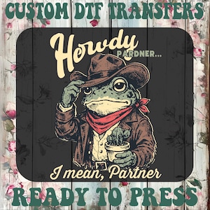 May include: DTF transfer with a cartoon frog in cowboy attire, including a hat and a cactus. Text says "Howdy Pardner... I mean, Partner" and "Custom DTF Transfers READY TO PRESS".