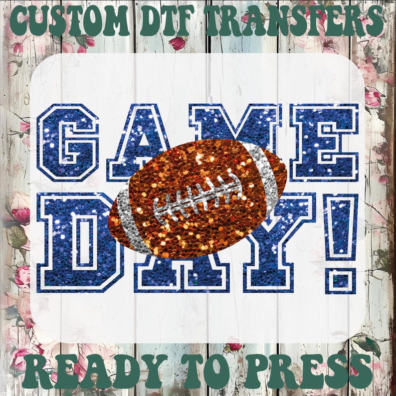 Puede incluir: Una transferencia DTF personalizada con el texto GAME DAY! en letras de bloque azul brillante. Un bal&oacute;n de f&uacute;tbol americano marr&oacute;n brillante con cordones plateados est&aacute; centrado sobre el texto, sobre un fondo blanco con flores.