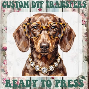 May include: A custom DTF transfer ready to press featuring a brown dachshund wearing tortoise shell glasses and a silver rhinestone necklace. The text CUSTOM DTF TRANSFERS appears at the top and READY TO PRESS appears at the bottom in green.