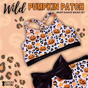 May include: A dance wear set featuring a white crop top with crisscross straps and matching briefs, both decorated with an orange pumpkin and black leopard print pattern. The briefs include a large, shiny black bow on the front waistband.
