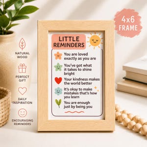 Op de afbeelding: Een lichtbruine fotolijst met de tekst "Little Reminders" en inspirerende berichten. De print bevat een lachende zon en diverse iconen. De lijst is 10 x 15 cm groot.