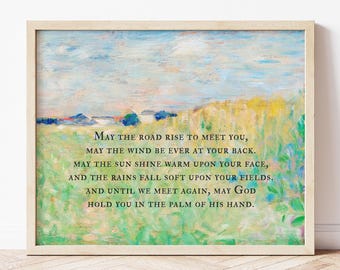 May include: A rectangular framed print featuring an impressionist-style landscape painting of a green field under a blue sky. Centered in dark text is the Irish blessing: May the road rise to meet you, may the wind be ever at your back.