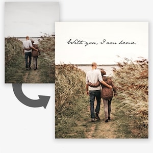 May include: A couple walks hand-in-hand down a path lined with tall grass. The text "With you, I am home." is written in black cursive on a white background.