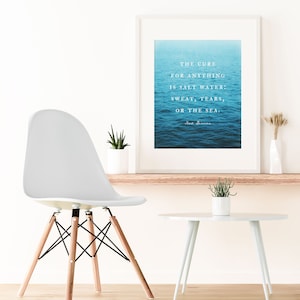 May include: A white framed print with a blue ocean background and a quote that reads "The cure for anything is salt water: sweat, tears, or the sea." The quote is attributed to "Sea Swimmer".