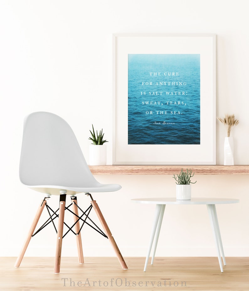May include: A white framed print with a blue ocean background and a quote that reads "The cure for anything is salt water: sweat, tears, or the sea." The quote is attributed to "Sea Swimmer".