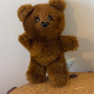 Puede incluir: Un juego de tres tazas de cerámica con un esmalte moteado de color crema. Cada taza presenta un diseño pintado a mano diferente: una hoja azul y verde, una flor amarilla y una baya roja. Las tazas tienen una forma simple y redondeada.