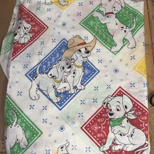 Peut inclure: Un tissu blanc avec un motif répétitif de chiots dalmatiens et de bandanas en forme de losange aux couleurs rouge, vert, bleu et jaune. Les chiots sont représentés dans diverses poses, certains portant des chapeaux de cow-boy ou des foulards verts.