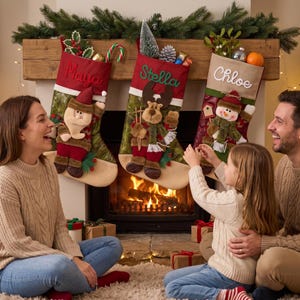 May include: Three personalised Christmas stockings hanging from a wooden mantel. The left stocking is red with the name Maya, the centre is red with the name Stella, and the right is beige with the name Chloe. Each features a plush holiday character.