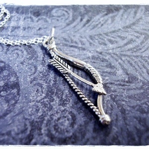 May include: A silver necklace with a bow and arrow pendant. The bow is made of twisted wire and the arrow has a feathered fletching.