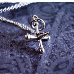 May include: A silver necklace with a four-pointed star pendant. The star has a pointed tip and rounded edges.