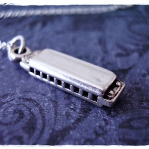 May include: A silver harmonica charm necklace. The harmonica charm is detailed with a silver chain and a silver loop for attaching to a necklace.