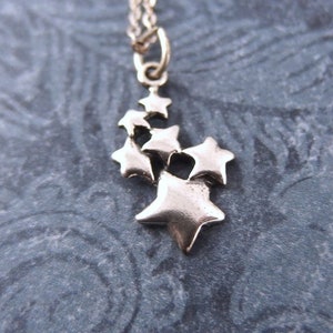 May include: Silver necklace with a charm of multiple silver stars clustered together.