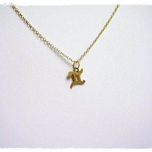 May include: A gold chain necklace with a gold pendant in the shape of the Gemini zodiac symbol.
