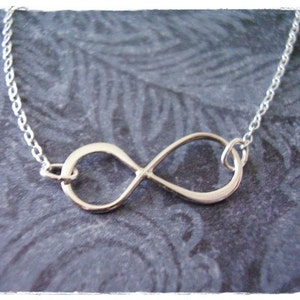 May include: A silver infinity symbol necklace with a delicate chain.