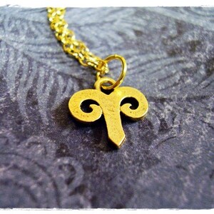 Peut inclure: Un collier en cha&icirc;ne dor&eacute;e avec un pendentif en or en forme de t&ecirc;te de b&eacute;lier.