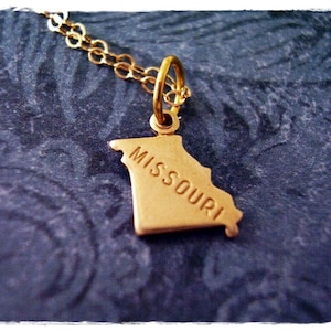 Könnte beinhalten: Goldkette mit einem Anhänger in Form des Bundesstaates Missouri. Der Anhänger trägt die Gravur "MISSOURI".