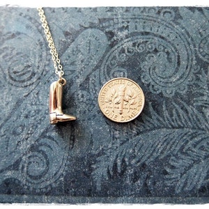 May include: A gold necklace with a boot charm. The boot is about the size of a dime.