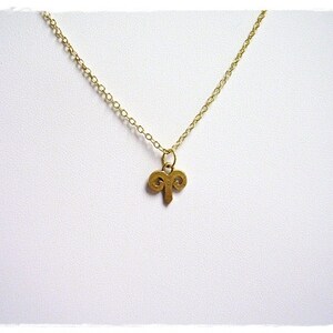 Peut inclure: Un collier en cha&icirc;ne dor&eacute;e avec un petit pendentif en or en forme de cornes de b&eacute;lier.