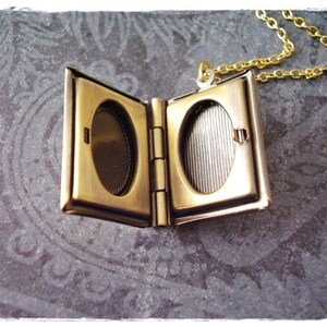 Peut inclure: Un collier avec un m&eacute;daillon en forme de livre dor&eacute;, avec une ouverture &agrave; charni&egrave;re. Le m&eacute;daillon a deux compartiments ovales pour des photos ou des souvenirs.