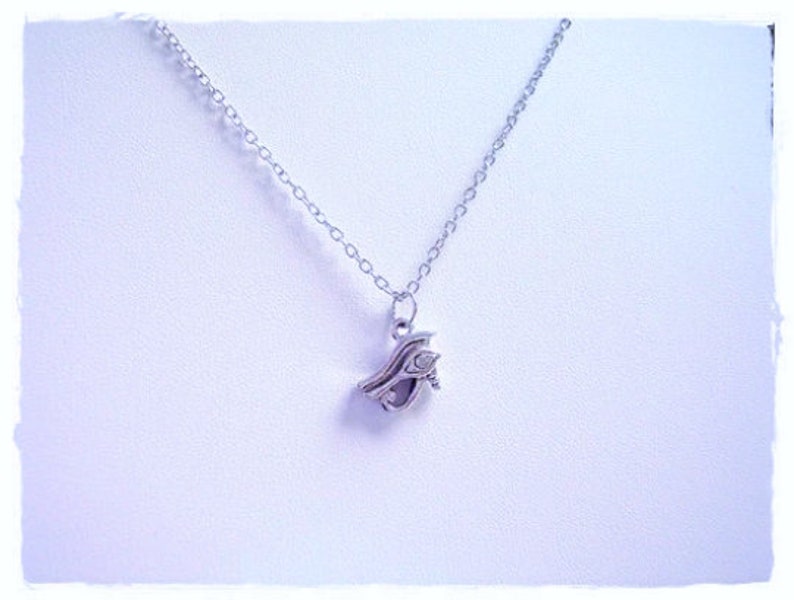 May include: A silver chain necklace with a silver pendant shaped like an eye with a small clear stone in the center.