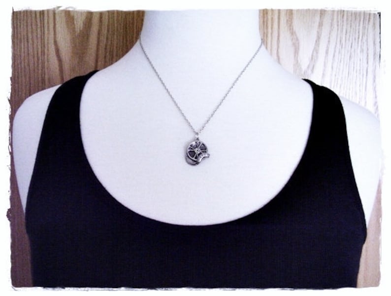 May include: A silver necklace with a flower pendant. The flower pendant has a detailed design and is made of metal.