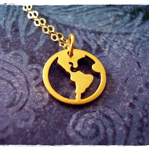 Puede incluir: Un collar de oro con un colgante con forma de la Tierra. El colgante está recortado para mostrar los continentes.