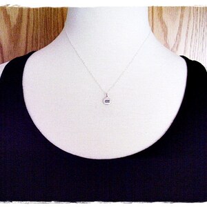 May include: A silver necklace with a round pendant featuring the astrological symbol for Aquarius.