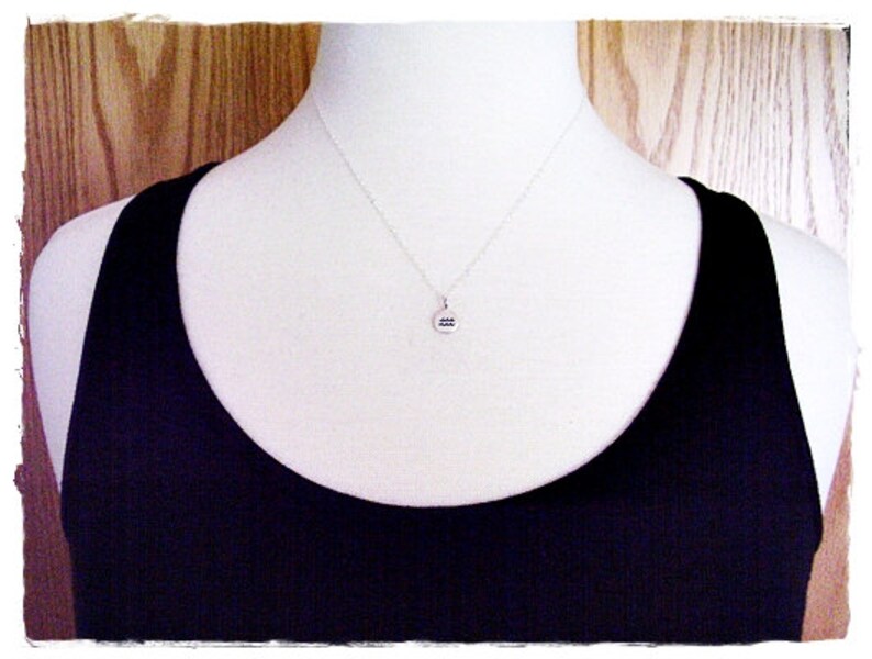 May include: A silver necklace with a round pendant featuring the astrological symbol for Aquarius.