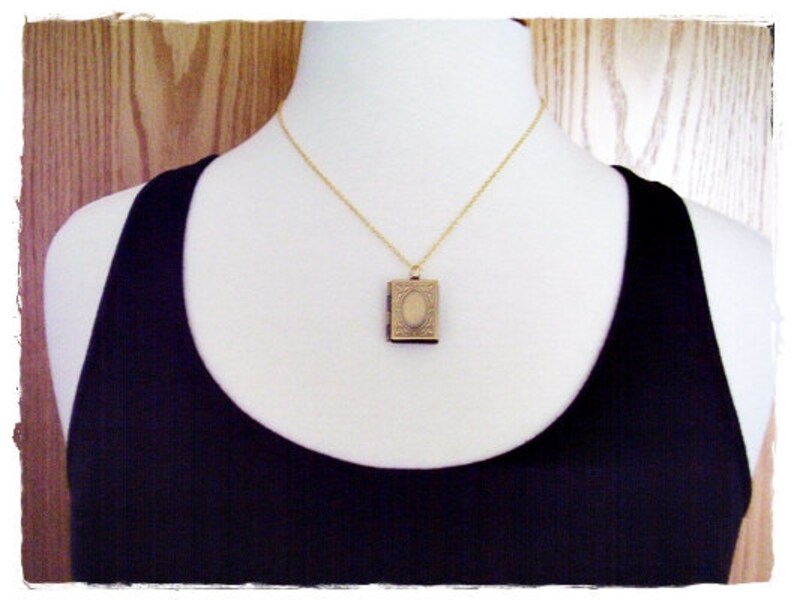 Peut inclure: Un collier en cha&icirc;ne dor&eacute;e avec un petit pendentif de m&eacute;daillon orn&eacute;. Le m&eacute;daillon est ferm&eacute; et pr&eacute;sente un design d&eacute;taill&eacute;.