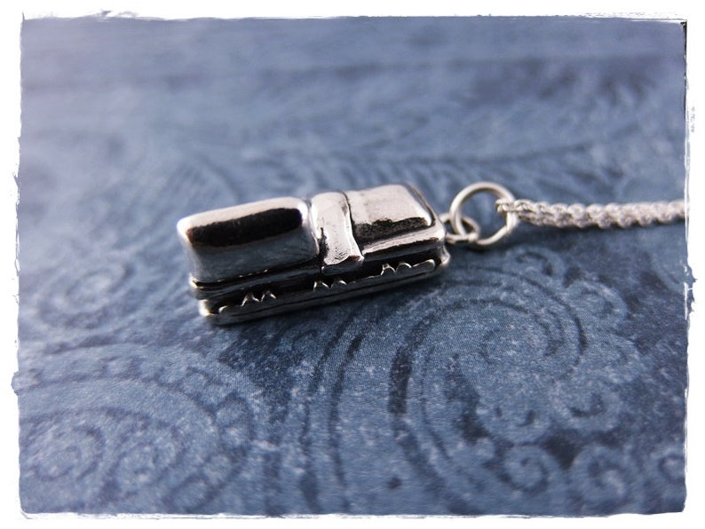 May include: A silver charm necklace featuring a miniature silver sleigh pendant. The sleigh has a detailed design with a curved roof and a small seat.