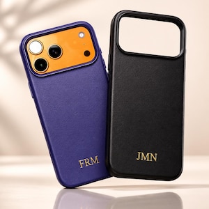 May include: Two phone cases: one purple with an orange camera area, and one black. Both cases have gold lettering. The purple case has "FRM" and the black case has "JMN".