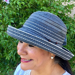 May include: A blue and white striped sun hat with a wide brim and a brown bead accent. The hat is made of a lightweight material and has a comfortable fit.
