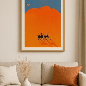 May include: Framed art print featuring a minimalist desert landscape. The artwork depicts two black animals with long shadows against an orange background, a blue sky, and a crescent moon. The print is in a wooden frame.