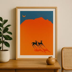 May include: Framed art print featuring a minimalist desert landscape. The artwork depicts two black animals running across an orange desert under a blue sky with a crescent moon. The print is in a wooden frame.