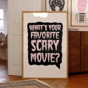 May include: A framed poster with a black speech bubble that says "What's your favourite scary movie?" in pink text. The poster has a white background.