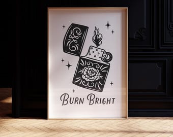 May include: Black and white framed art print featuring a detailed illustration of a vintage lighter with a floral design and the words "Burn Bright" in a decorative font. The lighter is open, with flames.