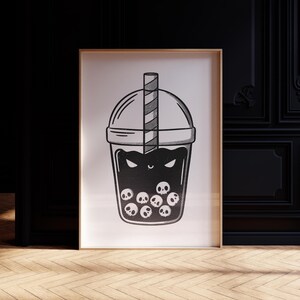 May include: Black and white illustration of a bubble tea drink with a straw. The drink is filled with skulls and has a spooky face. The artwork is framed in a wooden frame.