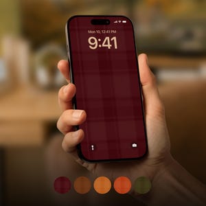 Op de afbeelding: Een smartphone met een donkerrood ruitjespatroon als achtergrond op het scherm. Het vergrendelscherm toont de datum Mon 10, de tijd 9:41 en iconen voor een zaklamp en camera. Daaronder staan vijf ronde kleurstalen in rood, bruin, oranje en groen.