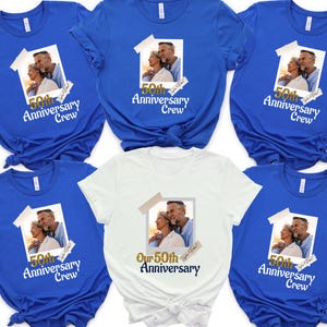 May include: A collection of blue and white t-shirts. Each shirt features a photo of a couple and the text "50th Anniversary Crew." One shirt reads "Our 50th Anniversary." The shirts are short-sleeved and suitable for a group celebrating a milestone.