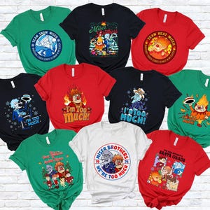 May include: A collection of colorful t-shirts featuring cartoon characters and text. The shirts are in various colors, including green, black, red, and white. The designs include the phrases "Team Snow Miser", "Miser Brothers", and "I'm Too Much!"