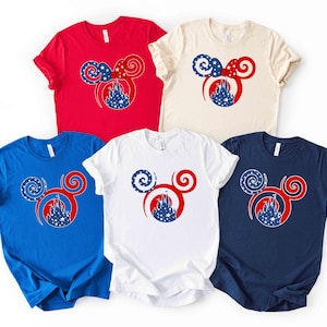 May include: Five short-sleeved t-shirts in red, blue, white, cream, and navy. Each shirt features a red Mickey Mouse head design with a patriotic theme, including a castle and star-filled accents.